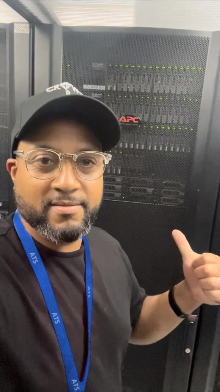 Bobby Cato, co-founder of Agile Tech Solutions, giving a thumbs up beside a rack of servers